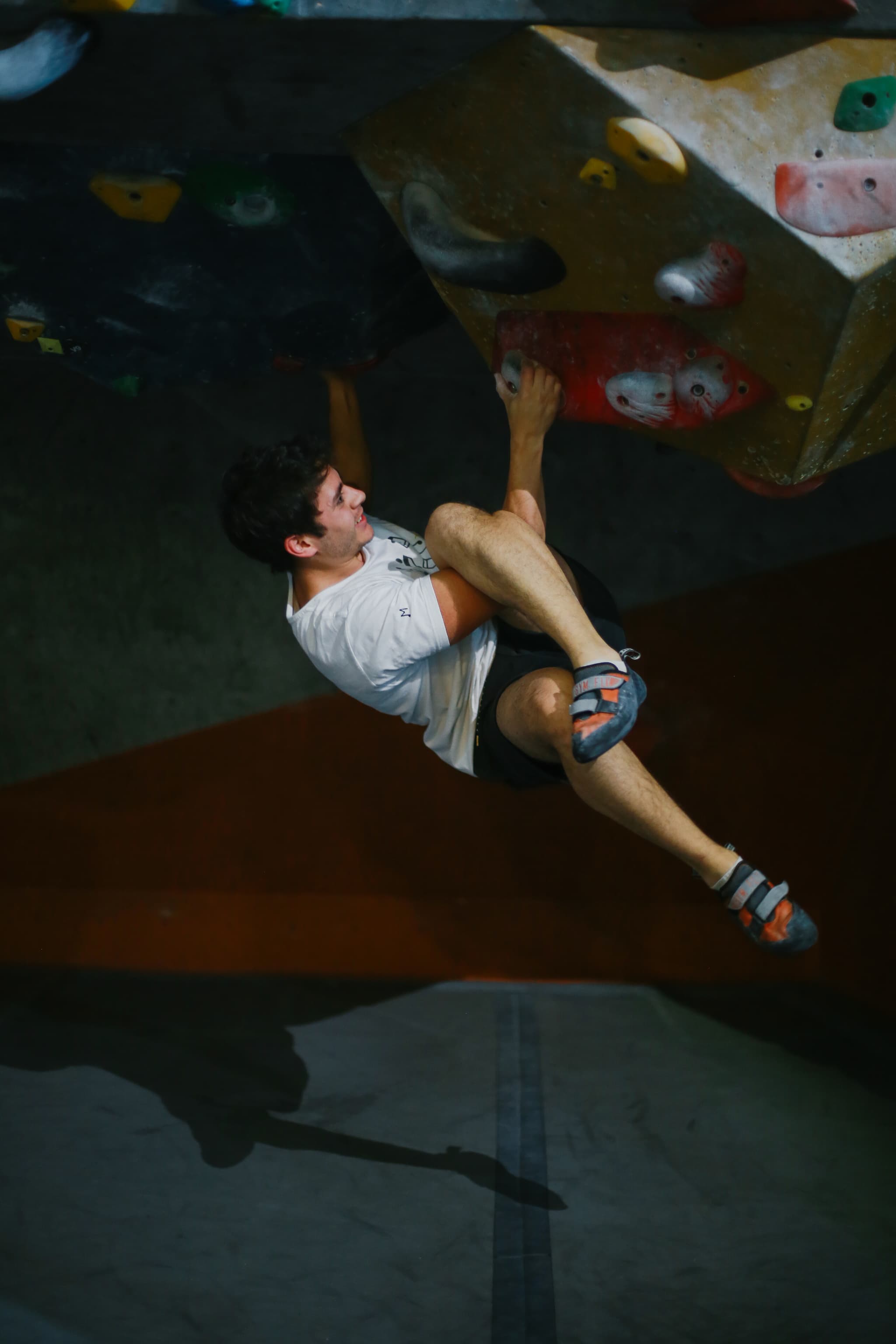 Escalador colgado alcanzando la cima del boulder
